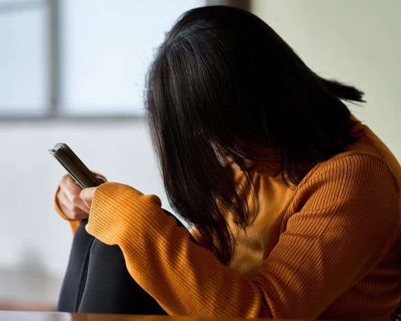 スマートフォンを見て気分が落ち込む女性