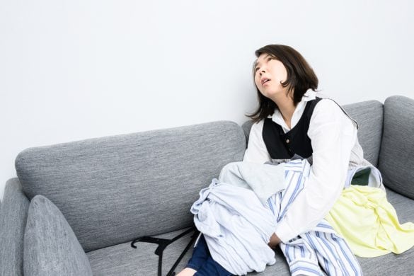 洗濯物を膝に乗せて天を仰ぐ女性