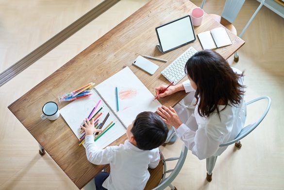 部屋で仕事をする母親とお絵描きをする子供