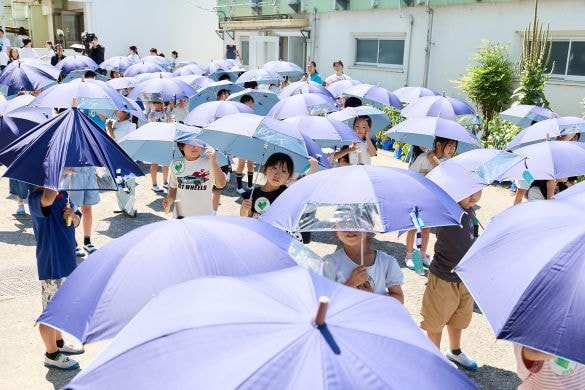  「こども気温 教室」で贈られた子ども日傘をさす児童たち