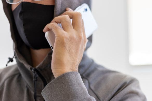 スマートフォンで電話をする顔を隠した怪しい男性