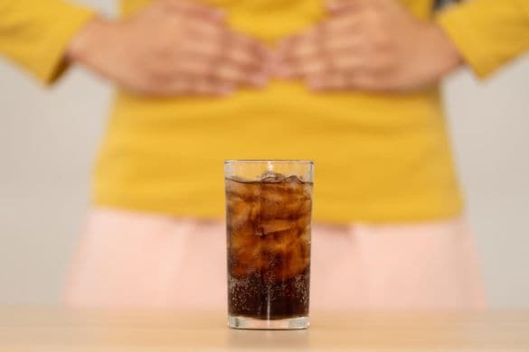 人工甘味料入りのドリンクを前にお腹をおさえる人