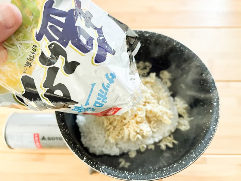 パックごはんの入った鍋に細かく砕いたインスタント麺を投入