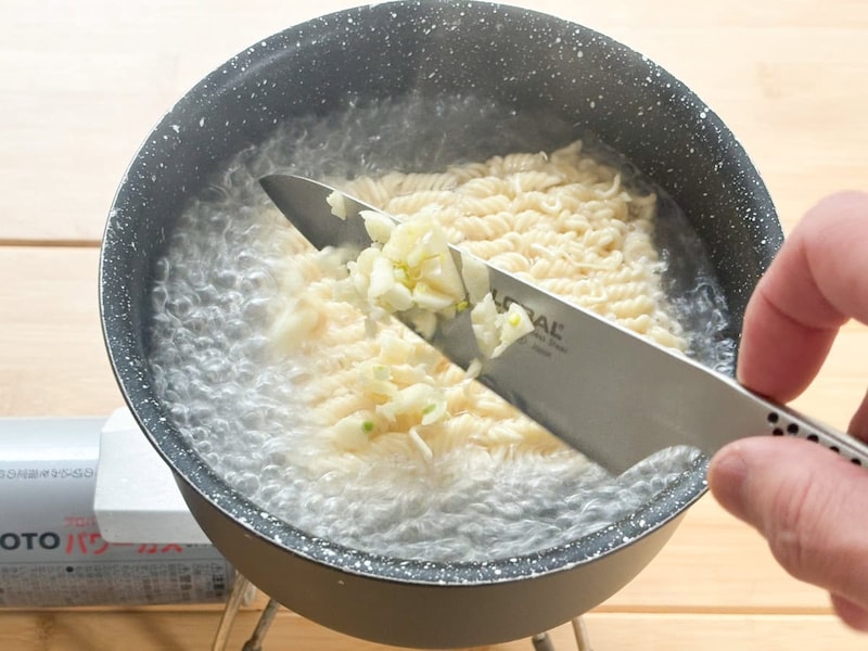インスタント麺に続いて、刻んだニンニクを投入し、次々と具材を加えていきます