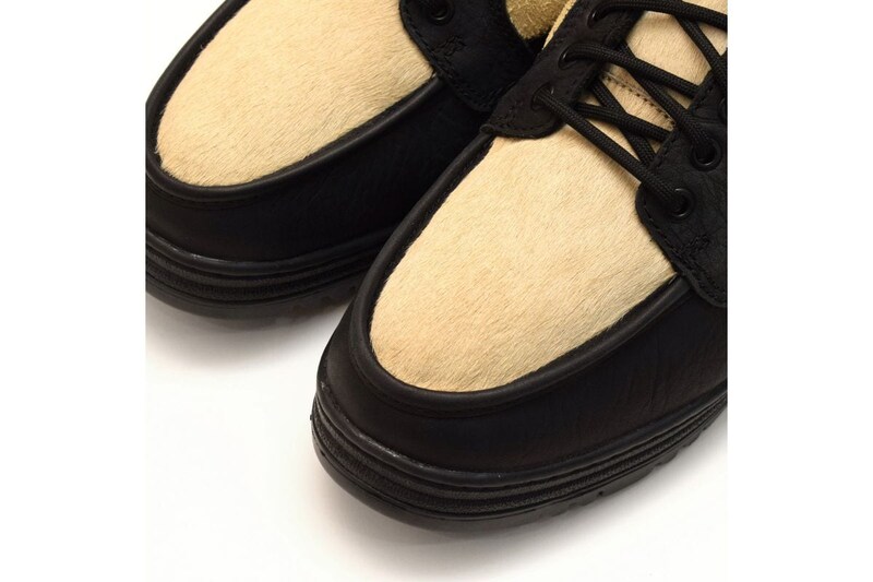 全体をブラックとクリームのコンビネーションカラーに仕上げ、アッパーのメイン素材に独特なシボ感のブラックレザーを採用