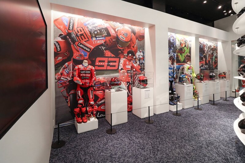 壁にはマルク・マルケス選手をはじめとする、SHOEIがサポートするMotoGPの現役ライダーやレジェンドライダーの本人用ヘルメット、レーシングスーツの展示が行われている