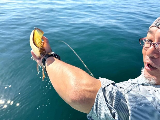 船縁でイカを掴み、逆さまにして水を吐かせる。 ©釣りビジョン