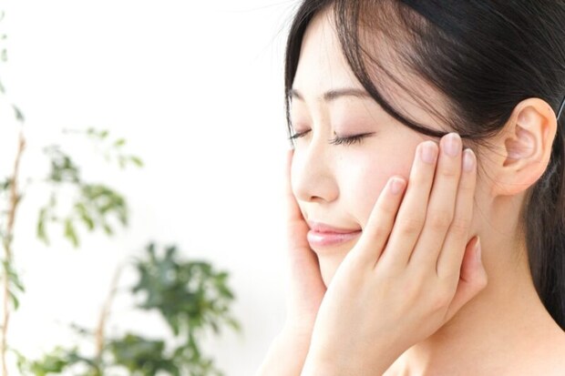 両手を頬に当てて目を閉じる女性