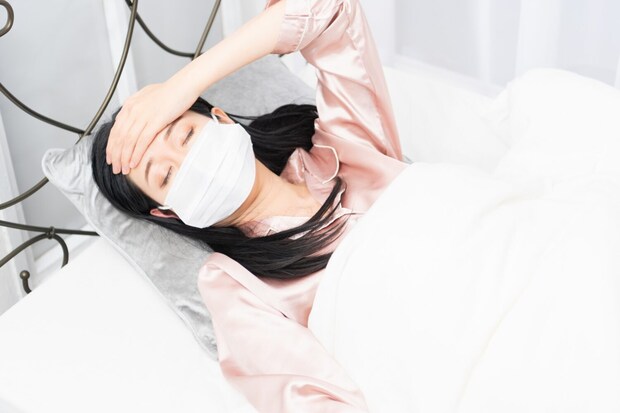 体調不良でベッドで寝込む女性