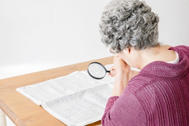 虫眼眼で新聞を読む高齢者の女性
