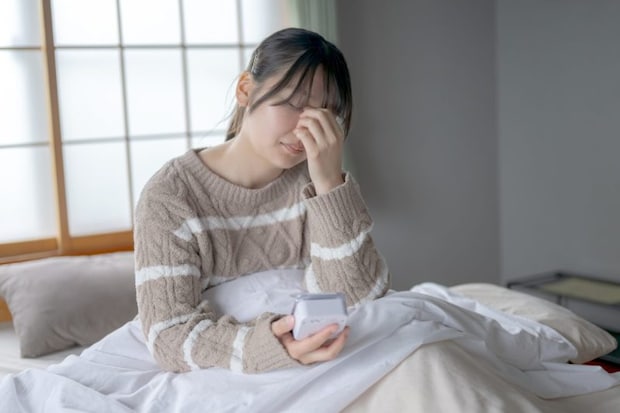 布団で電話を使う女性