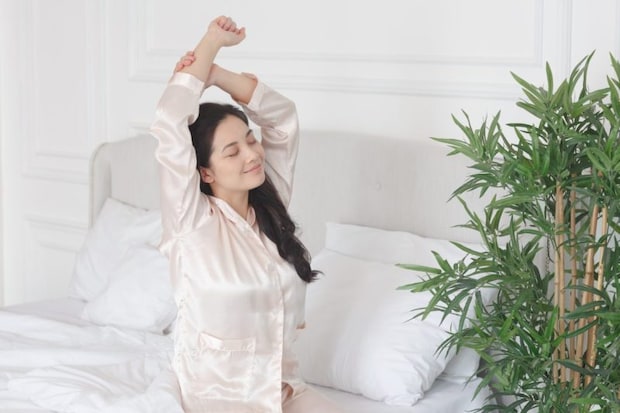 ベッドで伸びをする女性