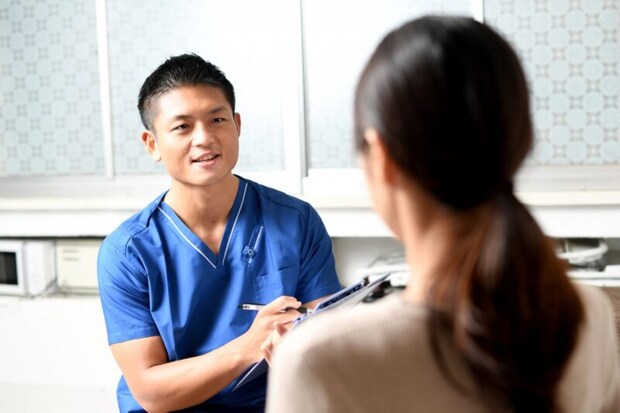 問診をするスクラブを着た若い男性の医療従事者