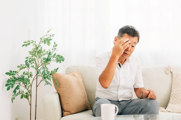 目の付近を押さえる男性