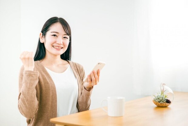 スマホを持ってガッツポーズする日本人女性
