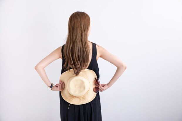 腰部を帽子で隠す女性