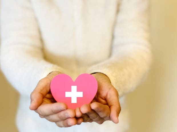 十字マーク入りのハート1つを両手で持つ女性