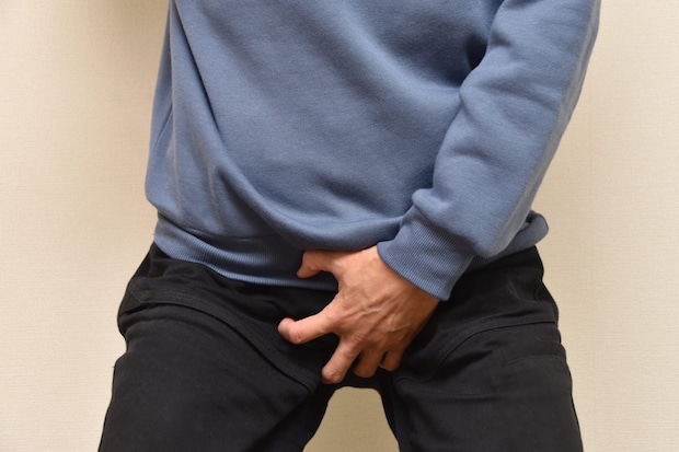 引け腰で股間を押さえる男
