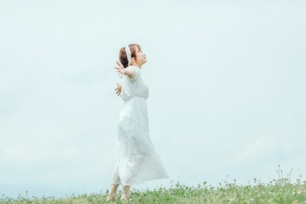 草むらで手を広げる女性