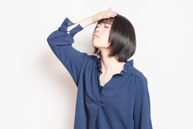 頭痛で痛む頭に手を当てている若い女性