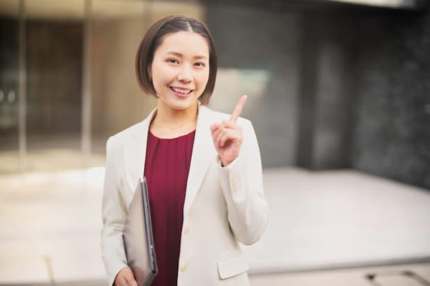 人差し指を立てる白いジャケットを着た女性2