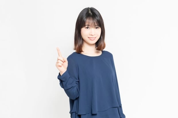 白い背景の前にたって、ポイントを示す若い女性