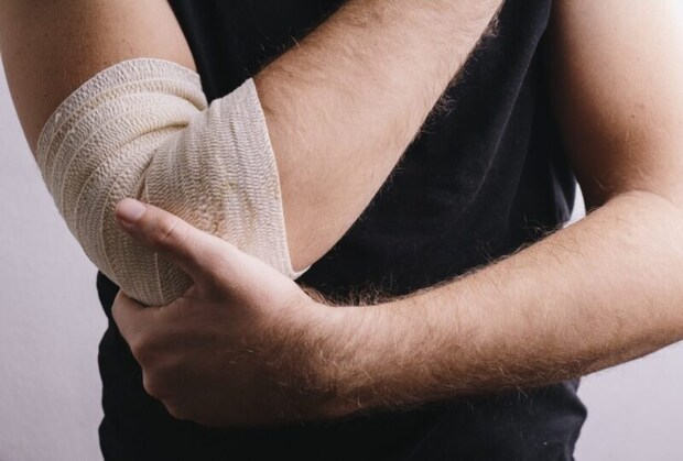 包帯を巻く肘を抑える人