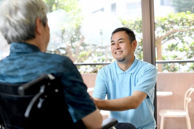 車椅子に乗る高齢者と男性の介護士