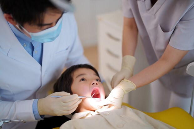 歯科衛生士が口を開けて検診する男性