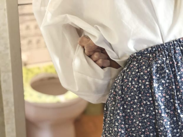 便器に向かってお腹を抱える女性