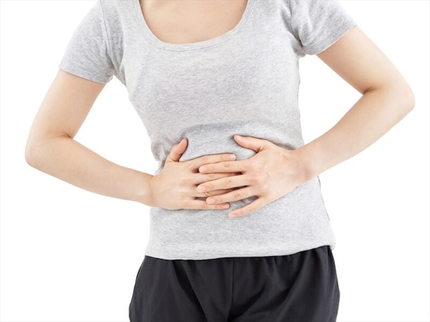 白背景で痛むお腹を押さえる女性