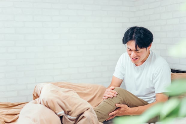 足をさわる男性