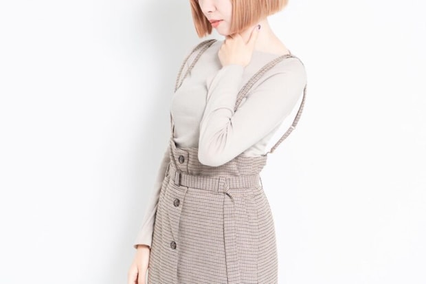 白背景の前に立って喉が痛いポーズをする若い女の子