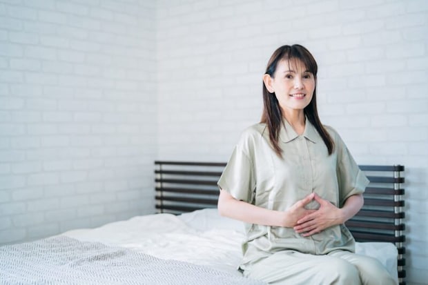 お腹を触るミドル世代の女性（笑顔）