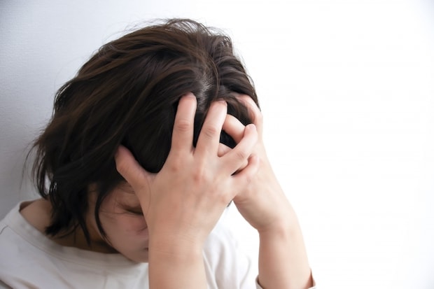 頭を抱えて落ち込む女性