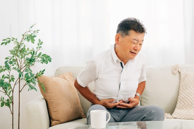 お腹をおさえる高齢者の男性