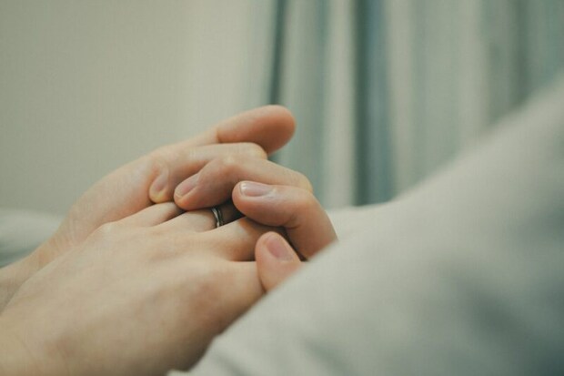 ベッドで手を繋ぐ男女の手