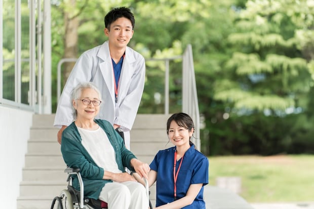 車椅子に乗った高齢者と医師・看護師