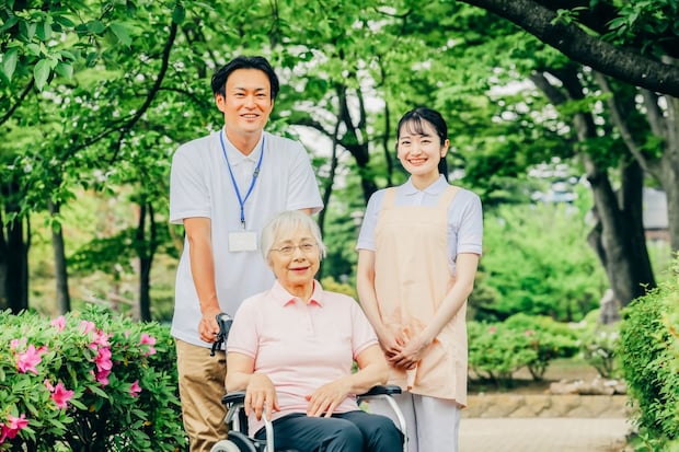 車椅子に乗った高齢者女性と男女スタッフ