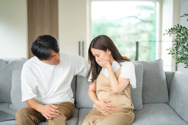 吐き気をもよおす妊婦と心配する男性