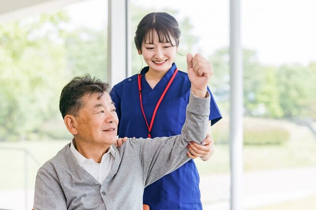 高齢者男性にリハビリ指導する理学療法士