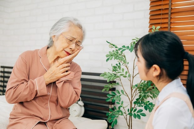 痛がる高齢者女性と介護士