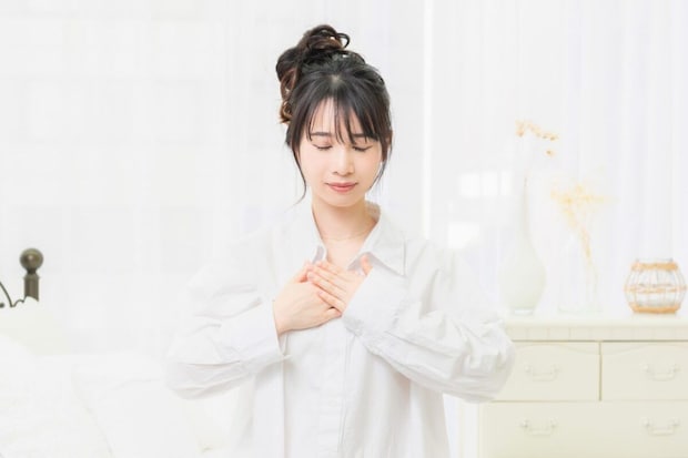 目をつむって胸を押さえる女性