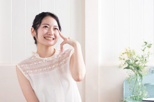 目を指さす笑顔の女性