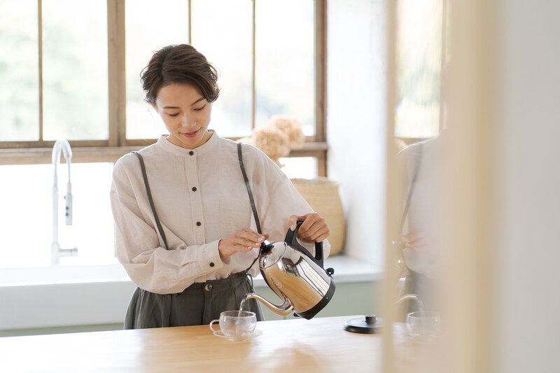 電気ケトルのお湯を耐熱カップに注ぐ女性