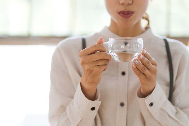 マグカップを手に持ち、吐息でお湯を冷ます女性