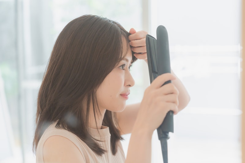 ヘアアイロンをかける女性