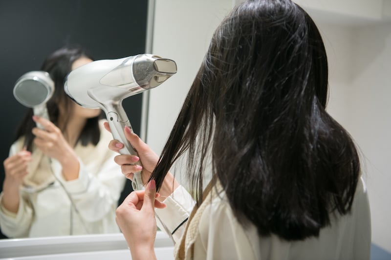 ドライヤーで髪を乾かす女性