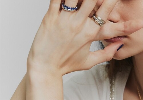 ゴールドとシルバーのリングを組み合わせて楽しむ女性