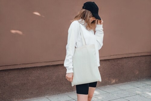 白いトートバッグを持つスポーティーなファッションの女性